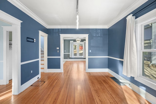 spare room with crown molding, baseboards, visible vents, and wood-type flooring