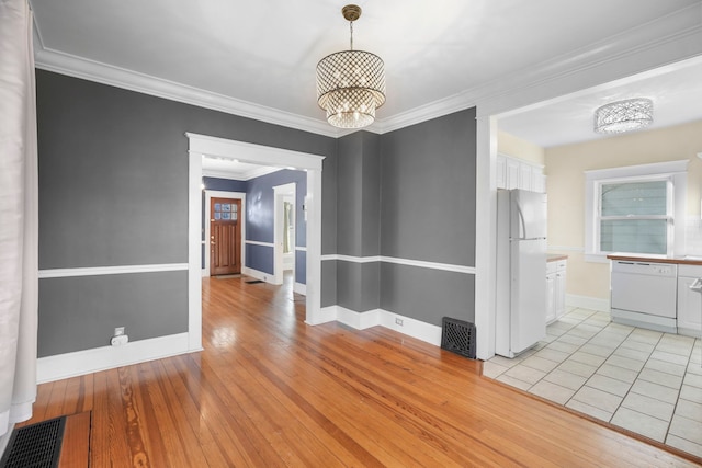 unfurnished dining area featuring visible vents, crown molding, baseboards, light wood-type flooring, and an inviting chandelier