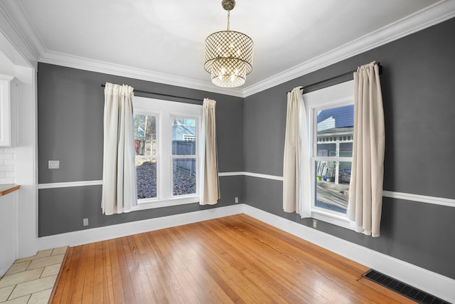 unfurnished room featuring light wood-type flooring, visible vents, baseboards, and a chandelier