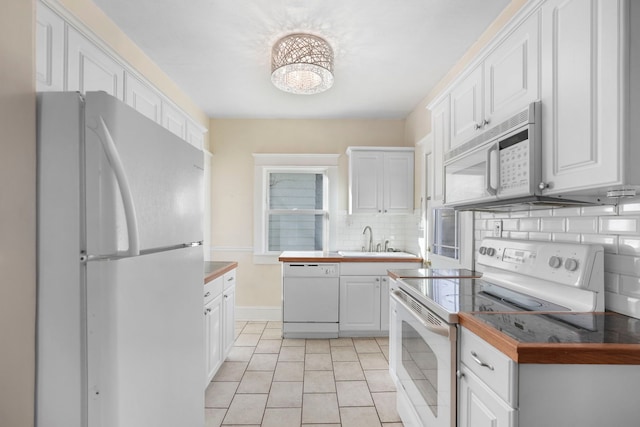 kitchen with a sink, white appliances, and white cabinetry