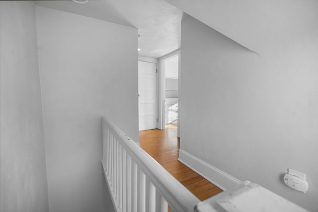 corridor featuring an upstairs landing, baseboards, and wood finished floors