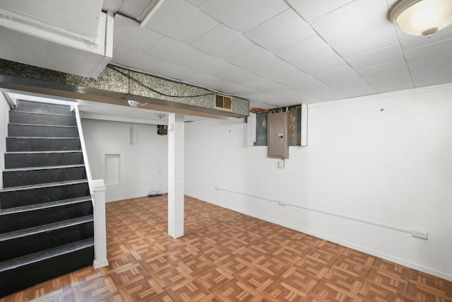 finished basement with electric panel, visible vents, stairs, and baseboards