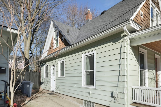 view of property exterior featuring a chimney, roof with shingles, and fence