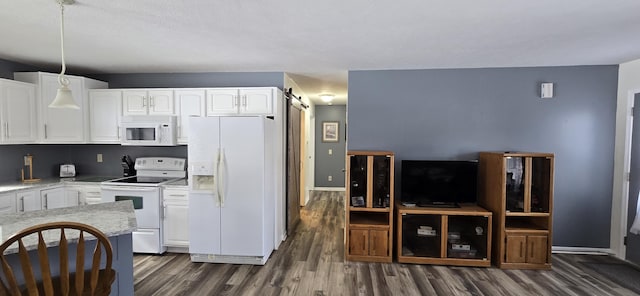 kitchen featuring dark wood finished floors, light countertops, a barn door, white cabinetry, and white appliances