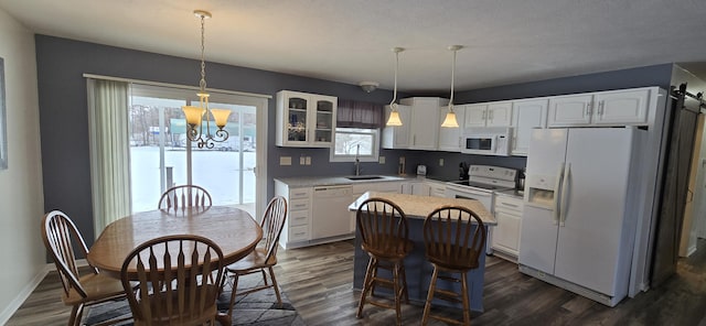 kitchen with dark wood finished floors, white cabinets, a kitchen island, a sink, and white appliances