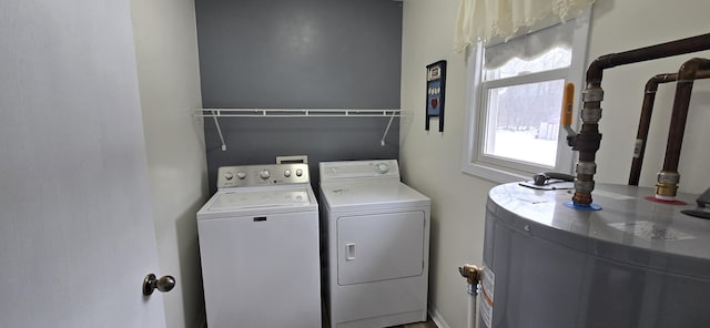 washroom featuring water heater, laundry area, and separate washer and dryer