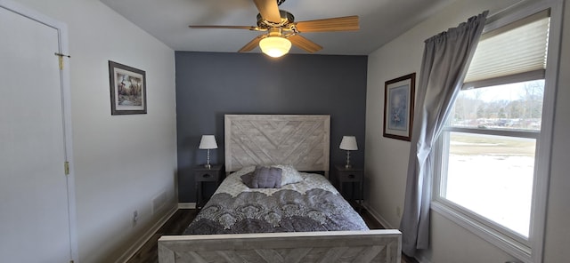 bedroom with multiple windows, ceiling fan, baseboards, and wood finished floors