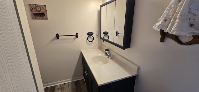 bathroom with baseboards, wood finished floors, and vanity