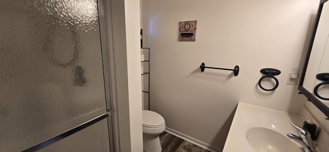 bathroom featuring a stall shower, baseboards, toilet, wood finished floors, and vanity