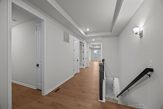 hall with recessed lighting, visible vents, wood finished floors, and an upstairs landing