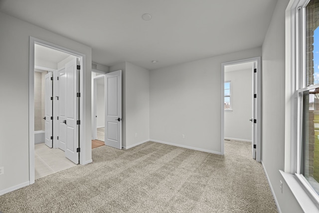 unfurnished bedroom featuring ensuite bath, baseboards, and carpet flooring