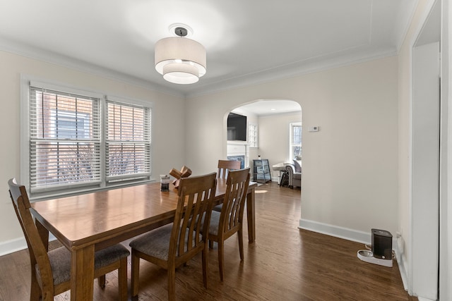 dining space with baseboards, arched walkways, dark wood finished floors, and ornamental molding