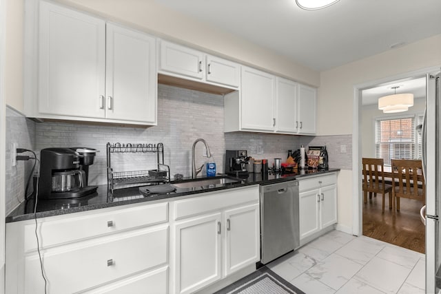 kitchen with marble finish floor, stainless steel dishwasher, white cabinetry, a sink, and dark stone counters