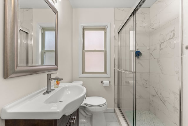 bathroom with toilet, a stall shower, baseboards, and vanity