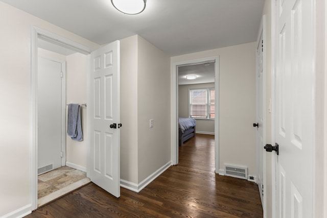 hall featuring visible vents, baseboards, and wood finished floors