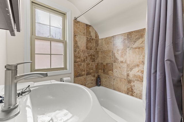 bathroom with lofted ceiling, a wealth of natural light, a sink, and shower / tub combo with curtain