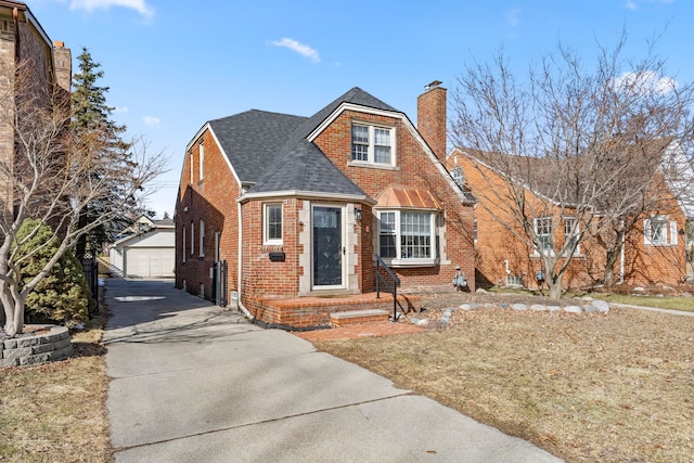 view of front of house featuring a garage, a shingled roof, a chimney, an outbuilding, and brick siding