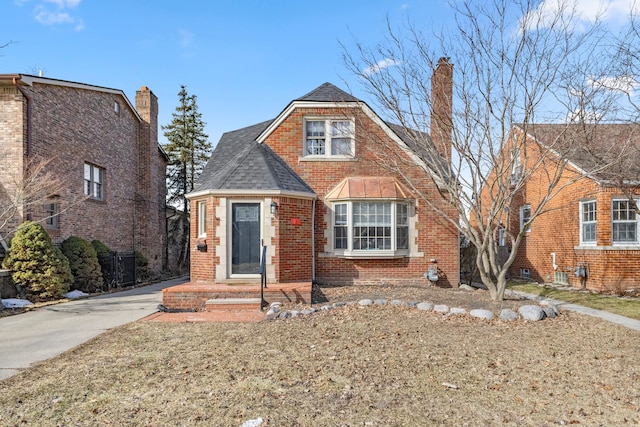 view of front of home featuring brick siding, a chimney, and roof with shingles