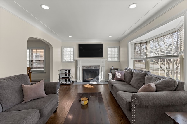 living room with recessed lighting, arched walkways, wood finished floors, and a high end fireplace