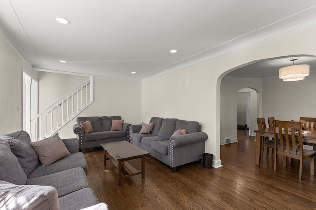 living area featuring arched walkways, ornamental molding, dark wood-style flooring, and stairs