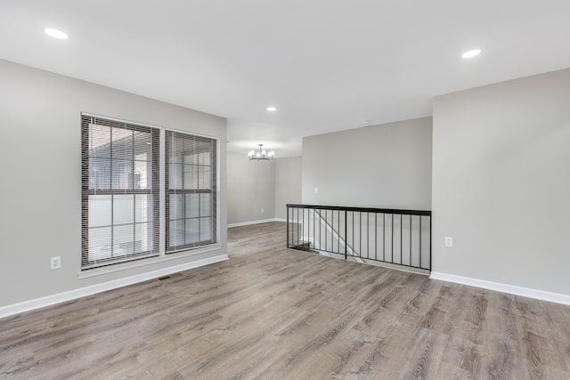 unfurnished room featuring recessed lighting, baseboards, a notable chandelier, and wood finished floors