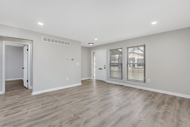 spare room featuring light wood-style floors, recessed lighting, visible vents, and baseboards