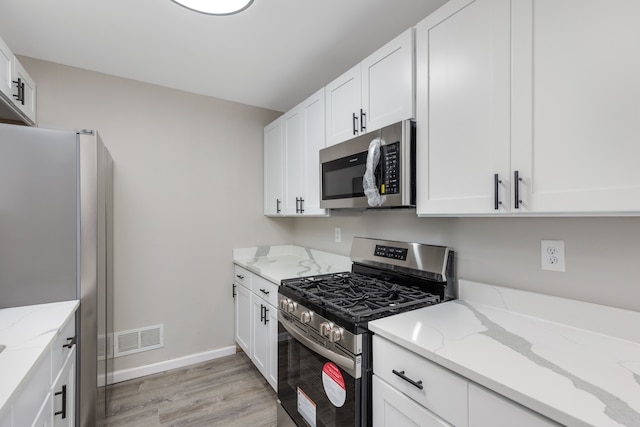 kitchen with stainless steel appliances, visible vents, light wood finished floors, and white cabinetry