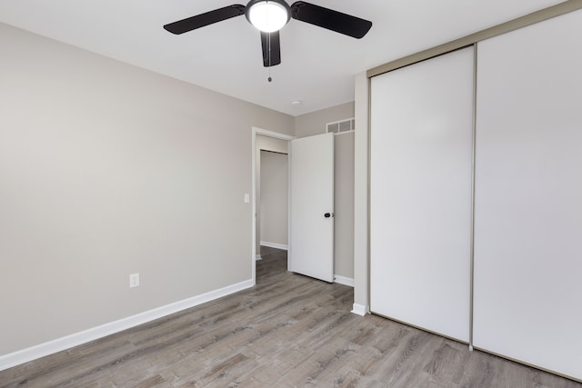 unfurnished bedroom with a closet, visible vents, ceiling fan, wood finished floors, and baseboards