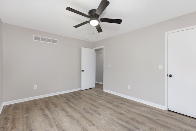 spare room featuring a ceiling fan, visible vents, baseboards, and wood finished floors