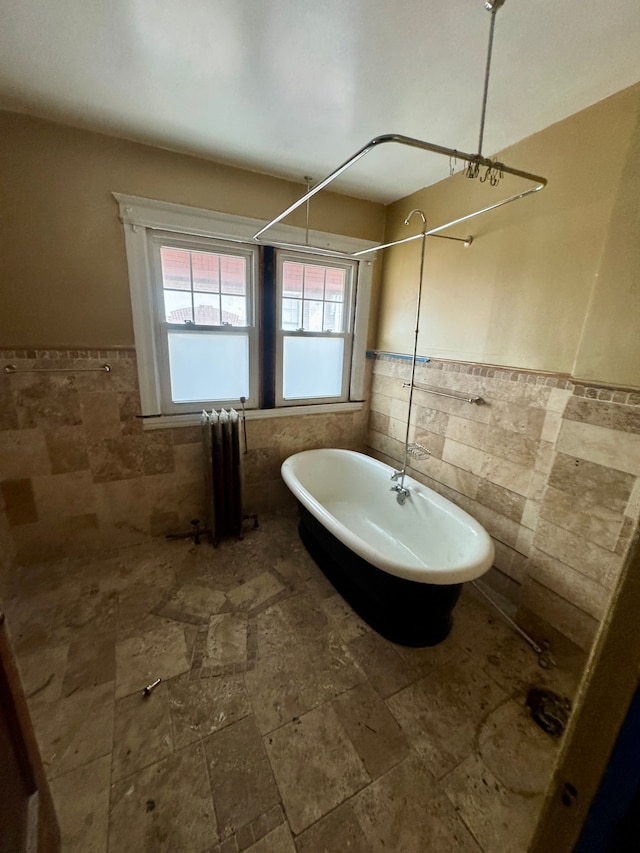 full bathroom featuring radiator heating unit, wainscoting, and tile walls