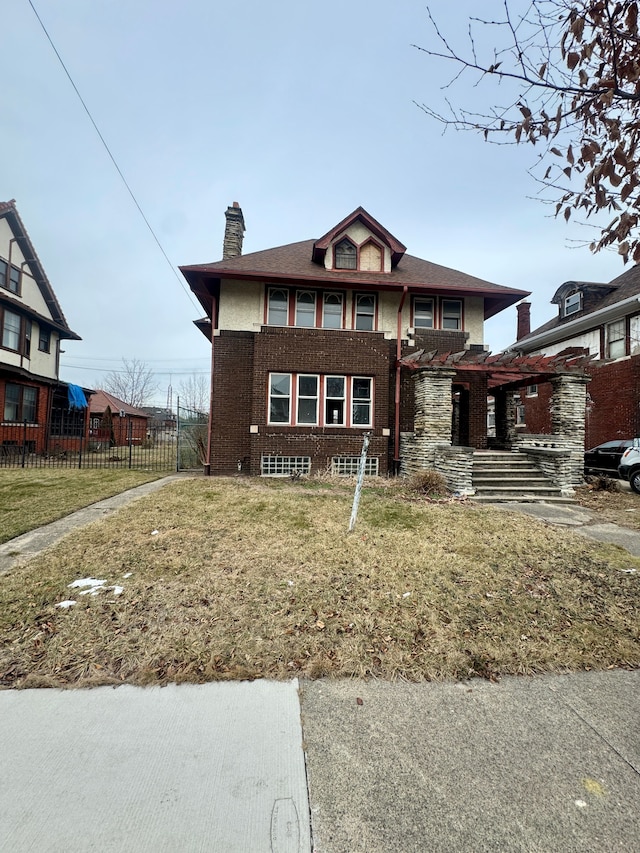 view of front of house featuring brick siding, a chimney, a front yard, and fence