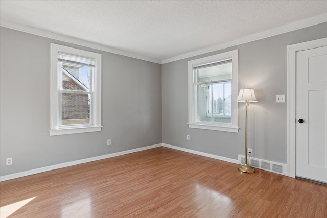 spare room featuring a textured ceiling, light wood-type flooring, and visible vents