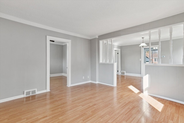 interior space featuring baseboards, light wood-style flooring, visible vents, and a textured ceiling