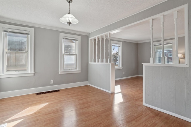 unfurnished room with visible vents, a textured ceiling, baseboards, and wood finished floors