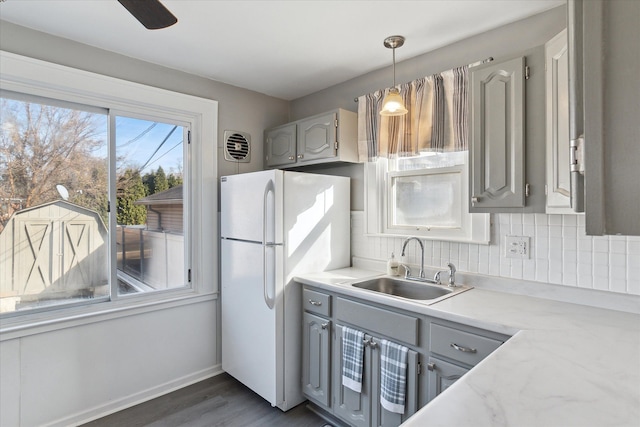 kitchen with decorative backsplash, gray cabinets, a sink, and freestanding refrigerator