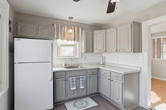 kitchen featuring freestanding refrigerator, gray cabinets, a sink, and decorative backsplash