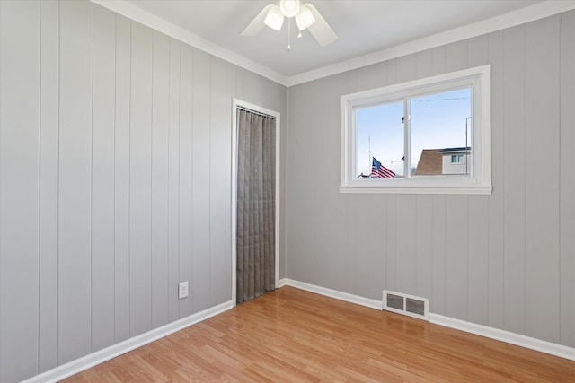 spare room featuring a ceiling fan, baseboards, visible vents, light wood-style floors, and ornamental molding