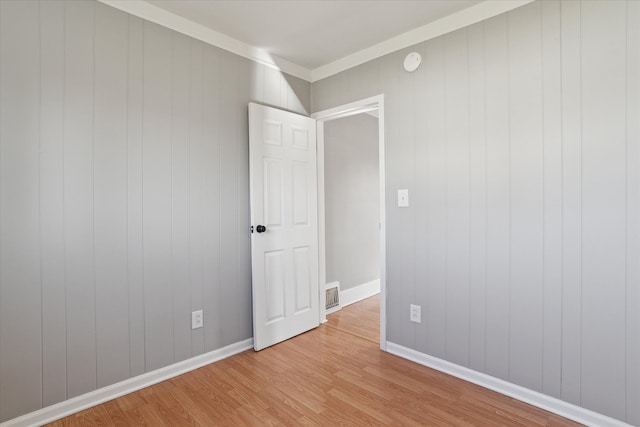 empty room with baseboards, visible vents, and light wood finished floors