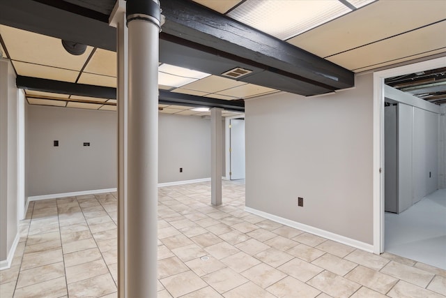 finished below grade area featuring a paneled ceiling, visible vents, and baseboards