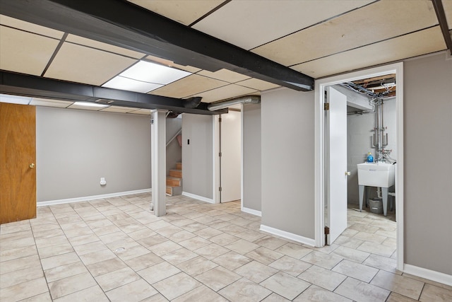 finished basement with stairway, light tile patterned flooring, a sink, and baseboards