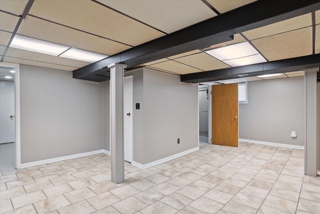 below grade area featuring tile patterned floors, a paneled ceiling, and baseboards