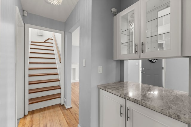 bar featuring stairway, light wood-style flooring, and baseboards