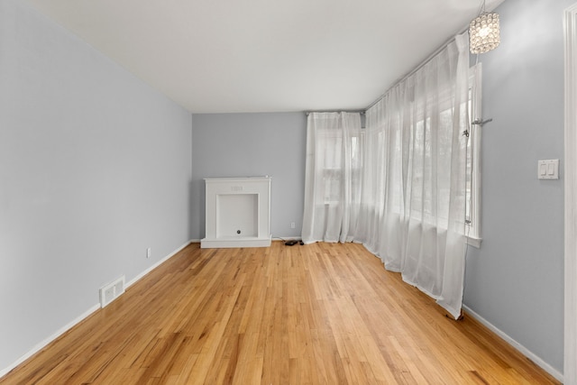 unfurnished living room featuring light wood-type flooring, visible vents, and baseboards