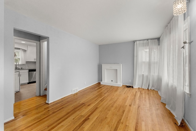 interior space with baseboards, a sink, visible vents, and light wood-style floors