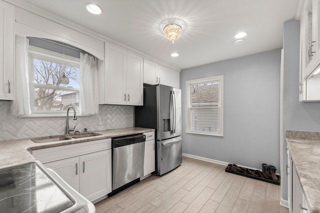 kitchen with tasteful backsplash, appliances with stainless steel finishes, light countertops, white cabinetry, and a sink