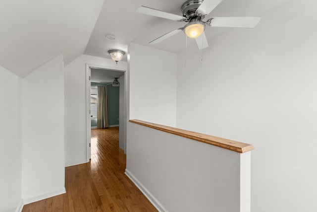 corridor with baseboards, vaulted ceiling, and wood finished floors