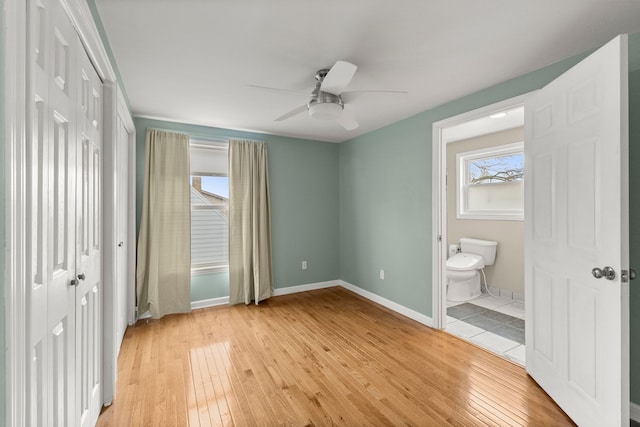 unfurnished bedroom featuring a ceiling fan, light wood-type flooring, connected bathroom, and baseboards