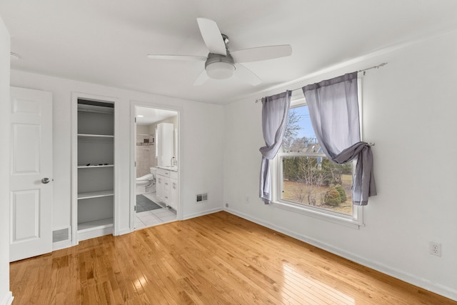 unfurnished bedroom with light wood-style floors, baseboards, visible vents, and connected bathroom