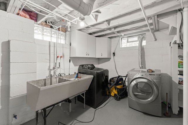 clothes washing area featuring independent washer and dryer, a sink, and cabinet space