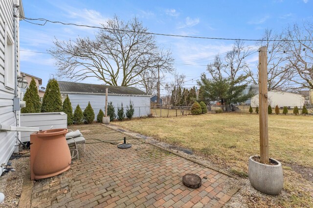 view of yard with fence, an outbuilding, and a patio